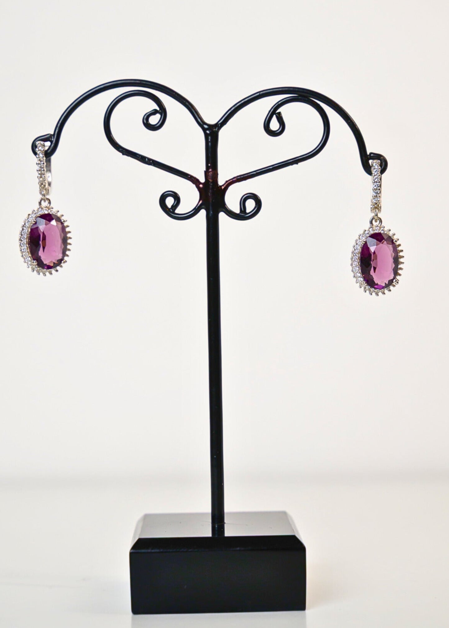 Black jewelry stand with pink earrings on a white background