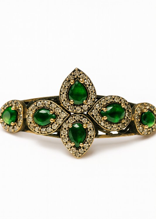 Gold bracelet with green gemstones on a white background