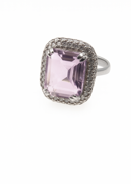 Ring with a pink gemstone and diamond-studded band on a white background