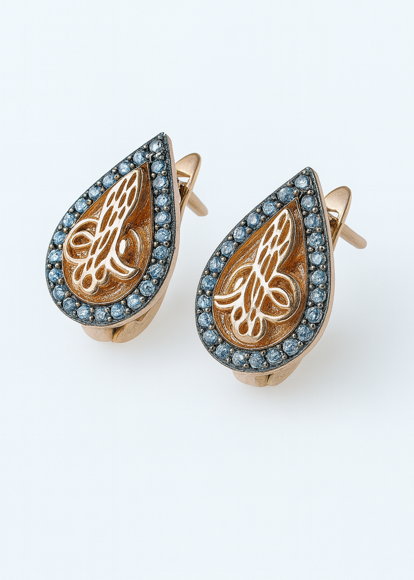 Pair of gold earrings with intricate designs on a white background