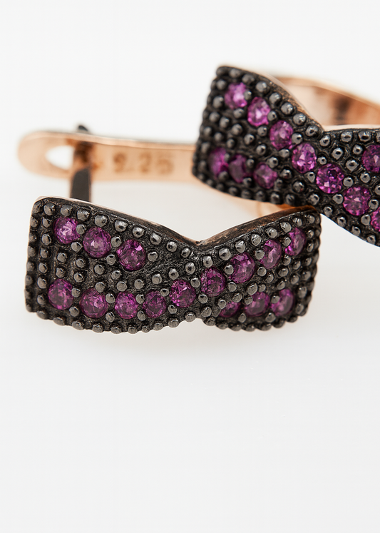 Bow-shaped jewelry piece with purple gemstones on a white background