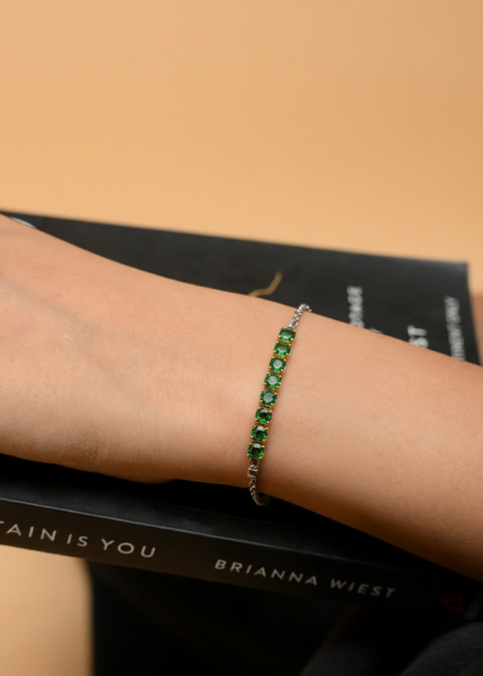 Green beaded bracelet on a wrist with a book in the background