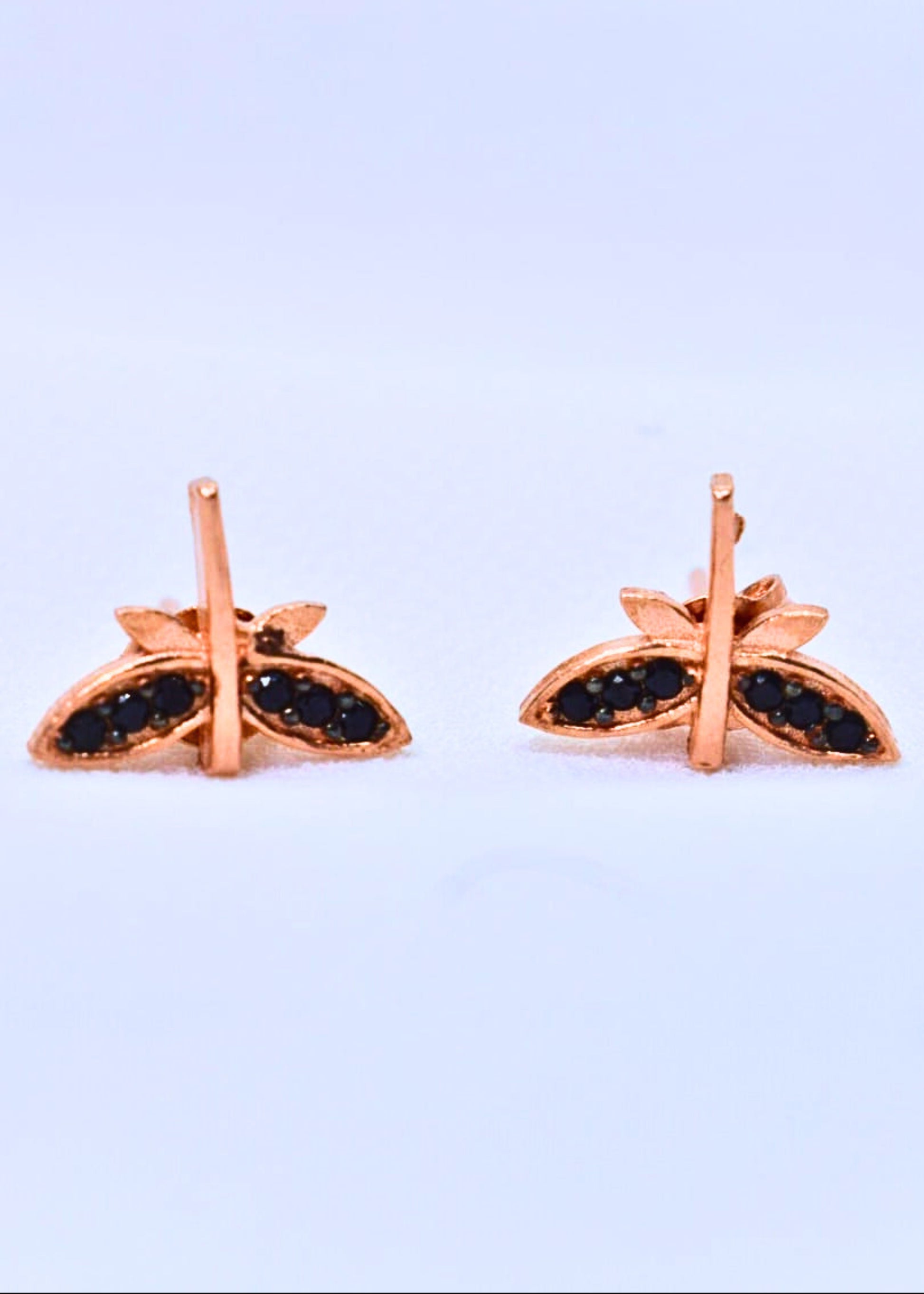Rose gold earrings with black gemstones on a light purple background