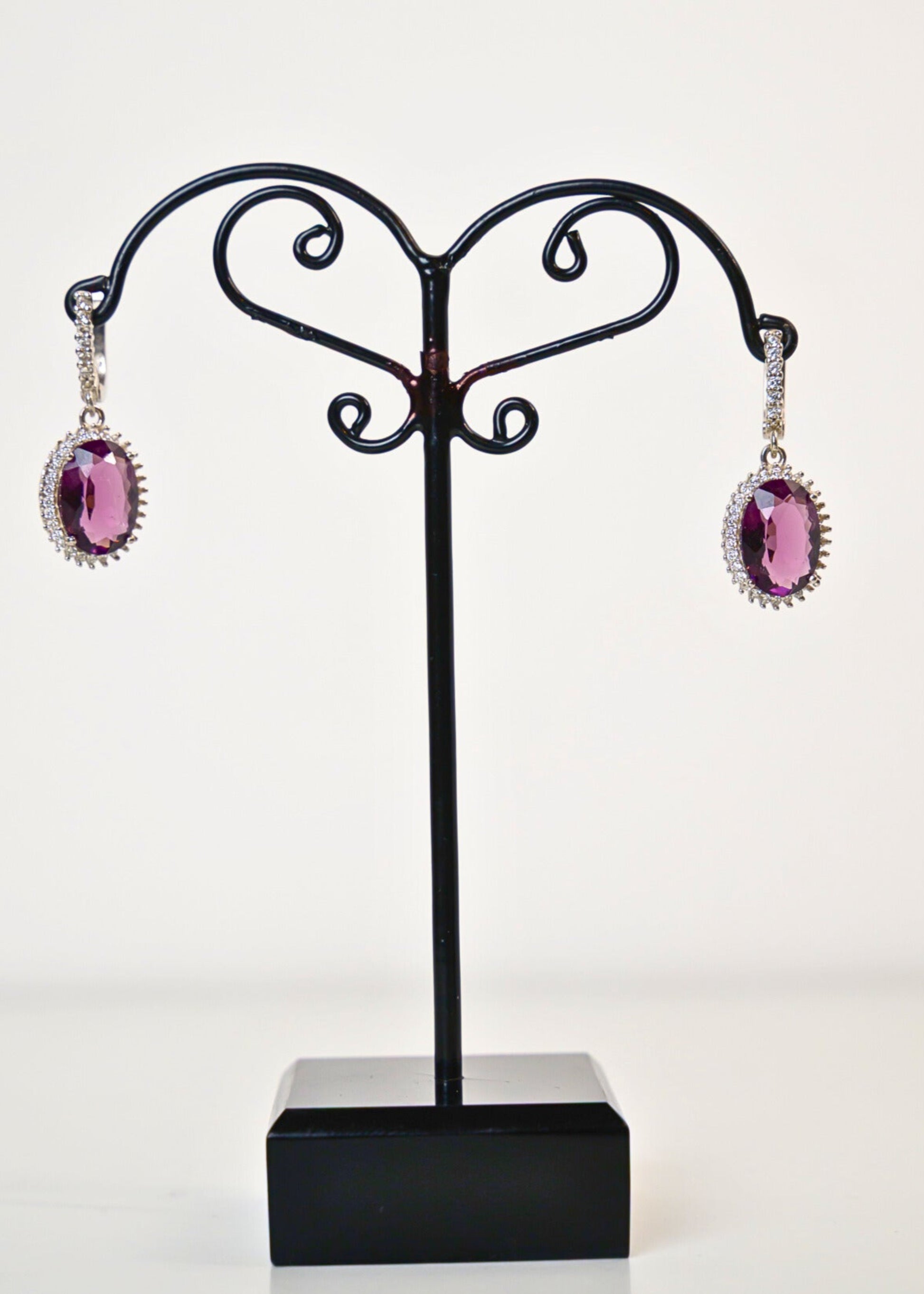 Black jewelry stand with pink earrings on a white background