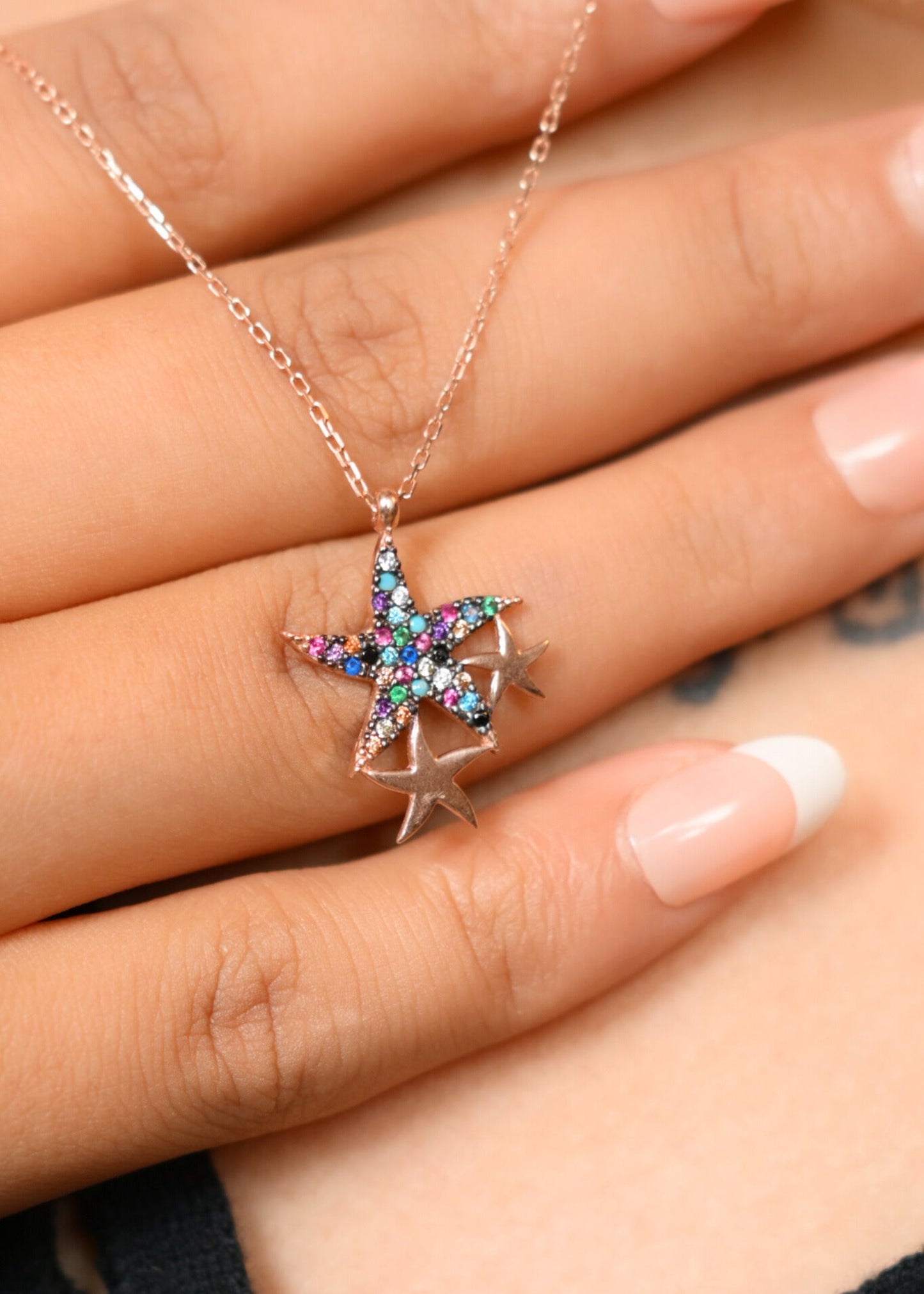 Star-shaped multicolored pendant on a chain held between fingers