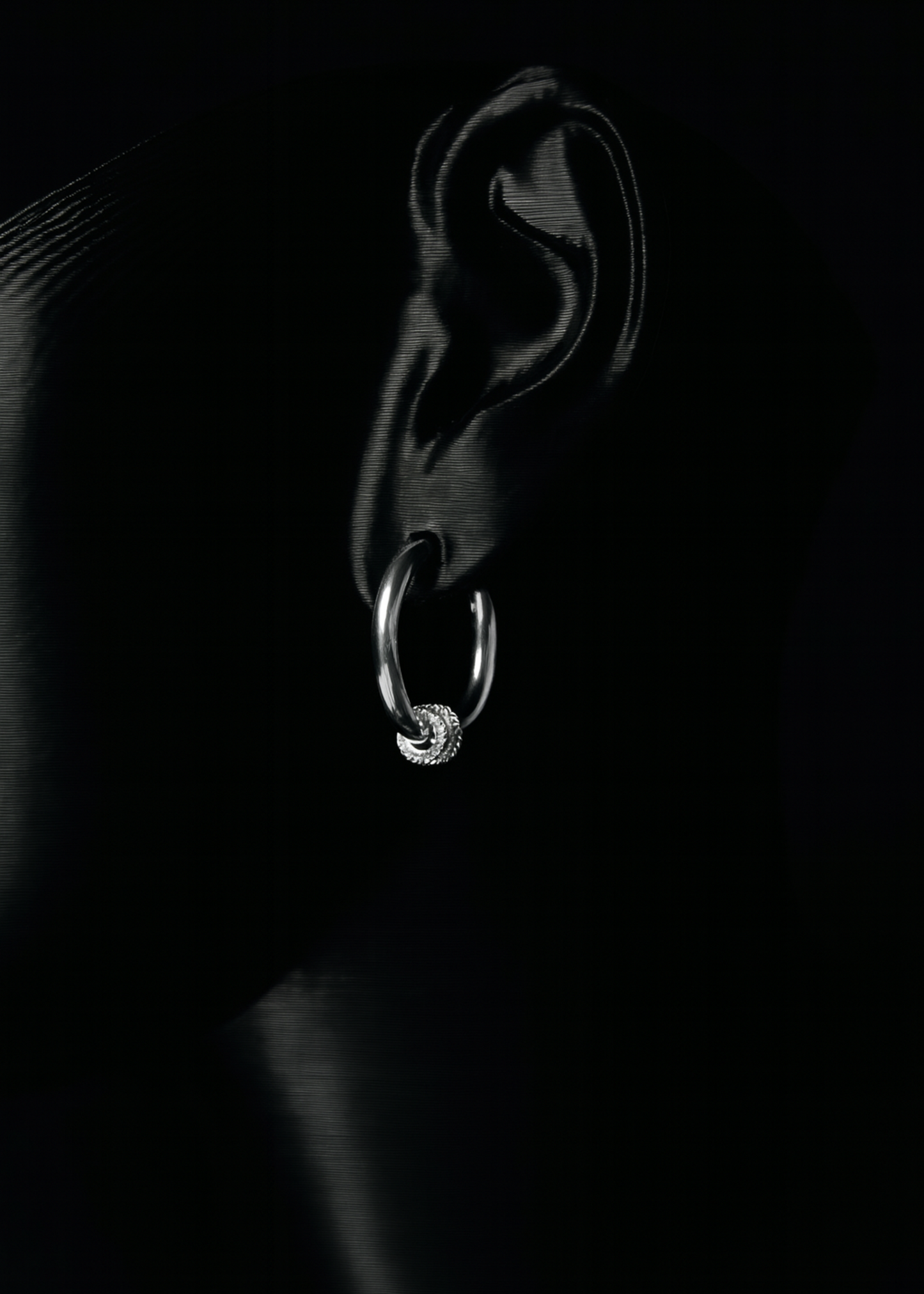 Silver hoop earring on a black background