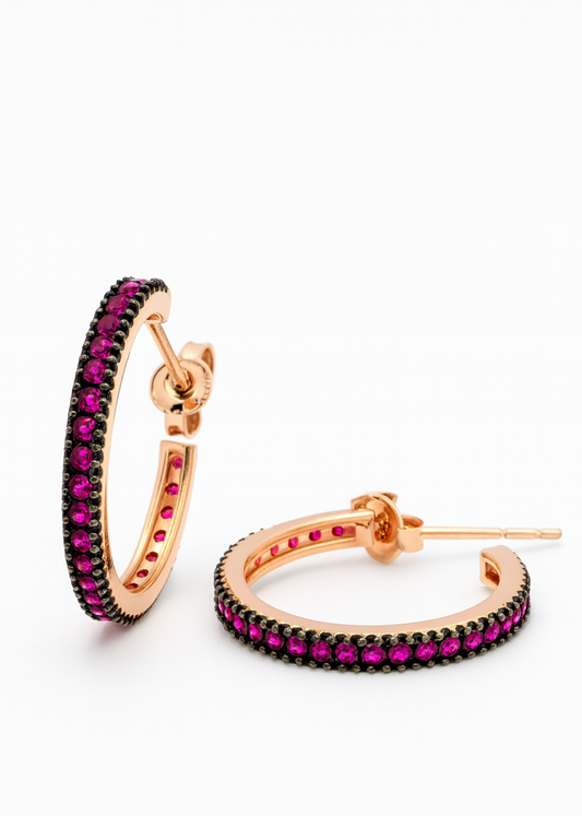 Rose gold hoop earrings with red gemstones on a white background