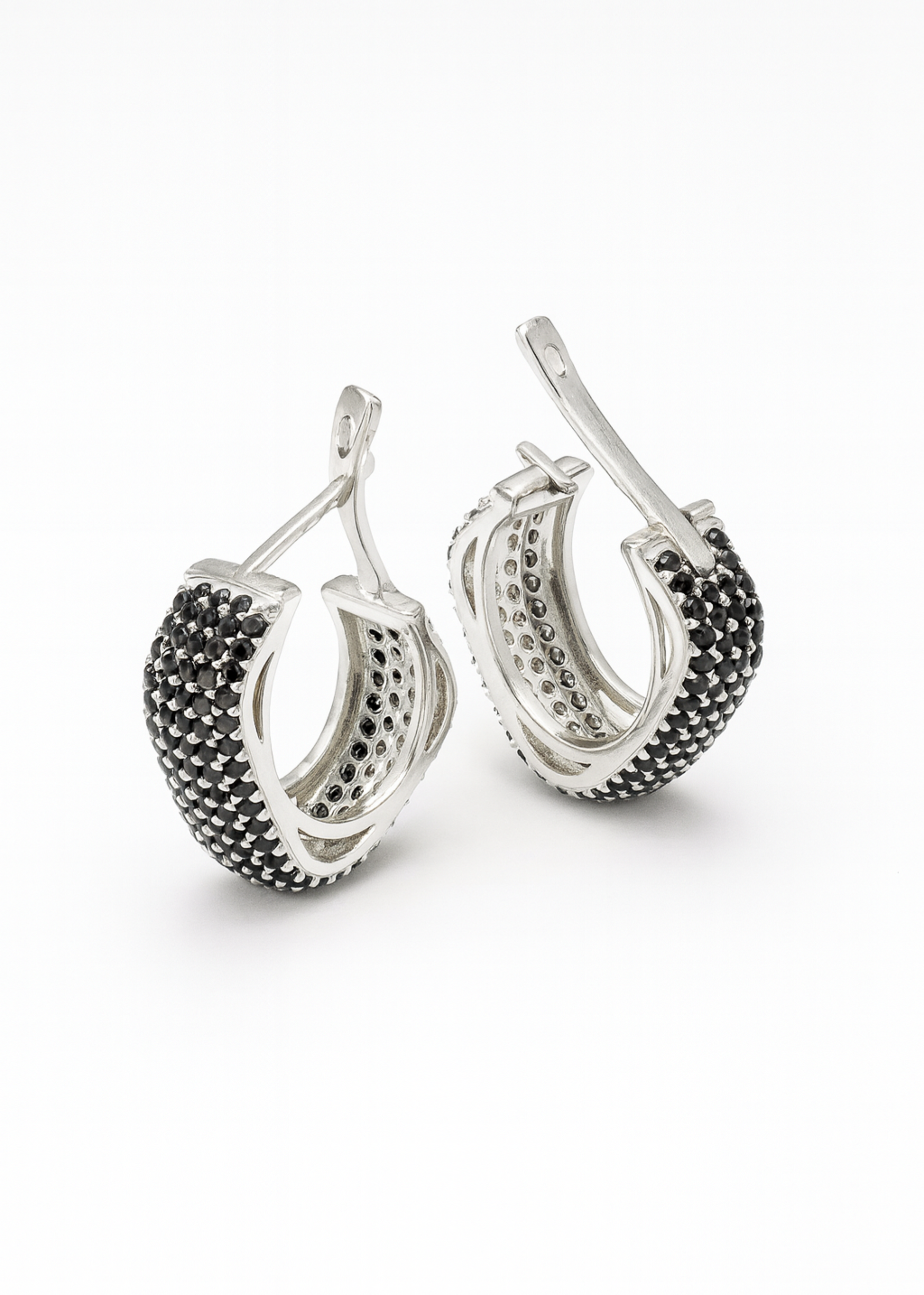 Pair of silver hoop earrings with black gemstones on a white background