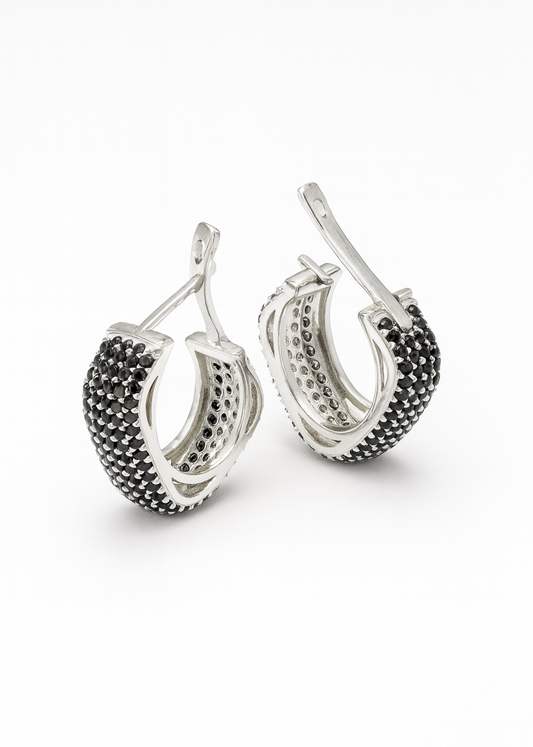 Pair of silver hoop earrings with black gemstones on a white background