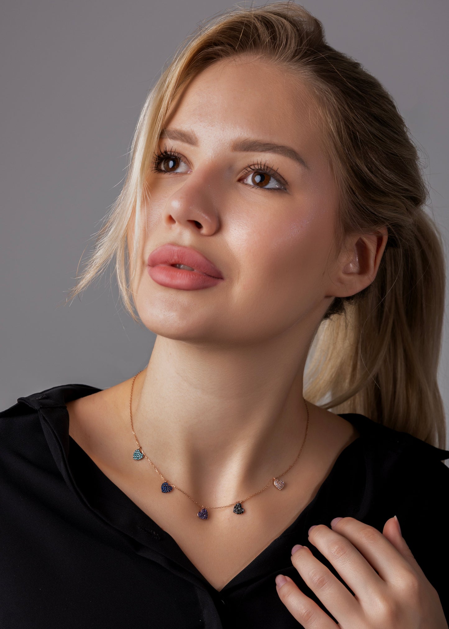 Woman wearing a necklace with a gray background