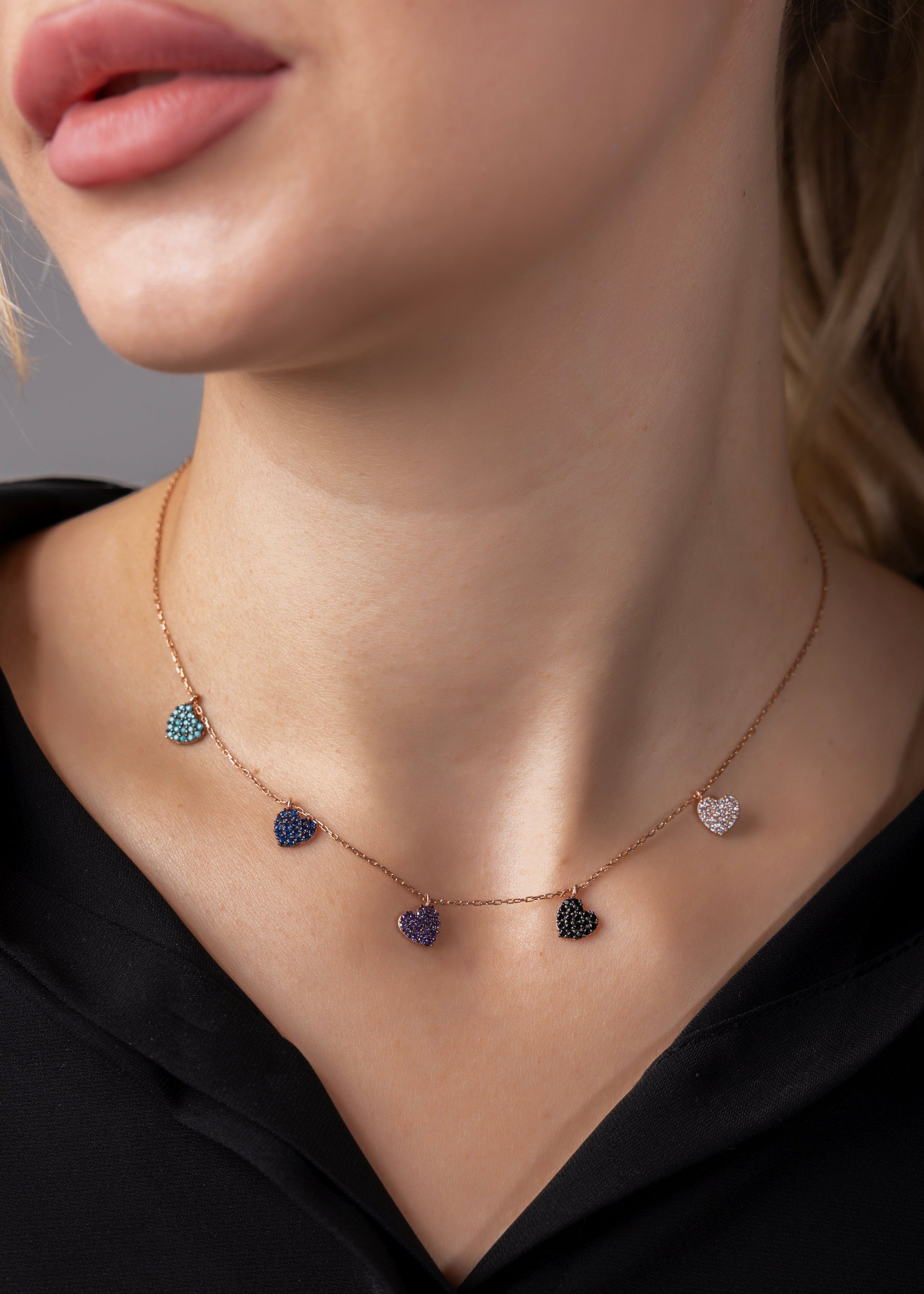 Necklace with heart-shaped gemstones worn by a person against a neutral background