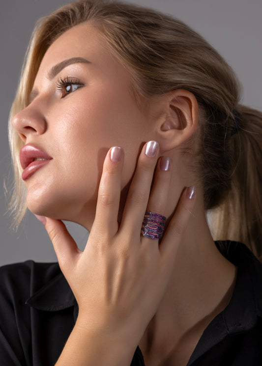 Woman wearing a ring with a purple gemstone against a neutral background