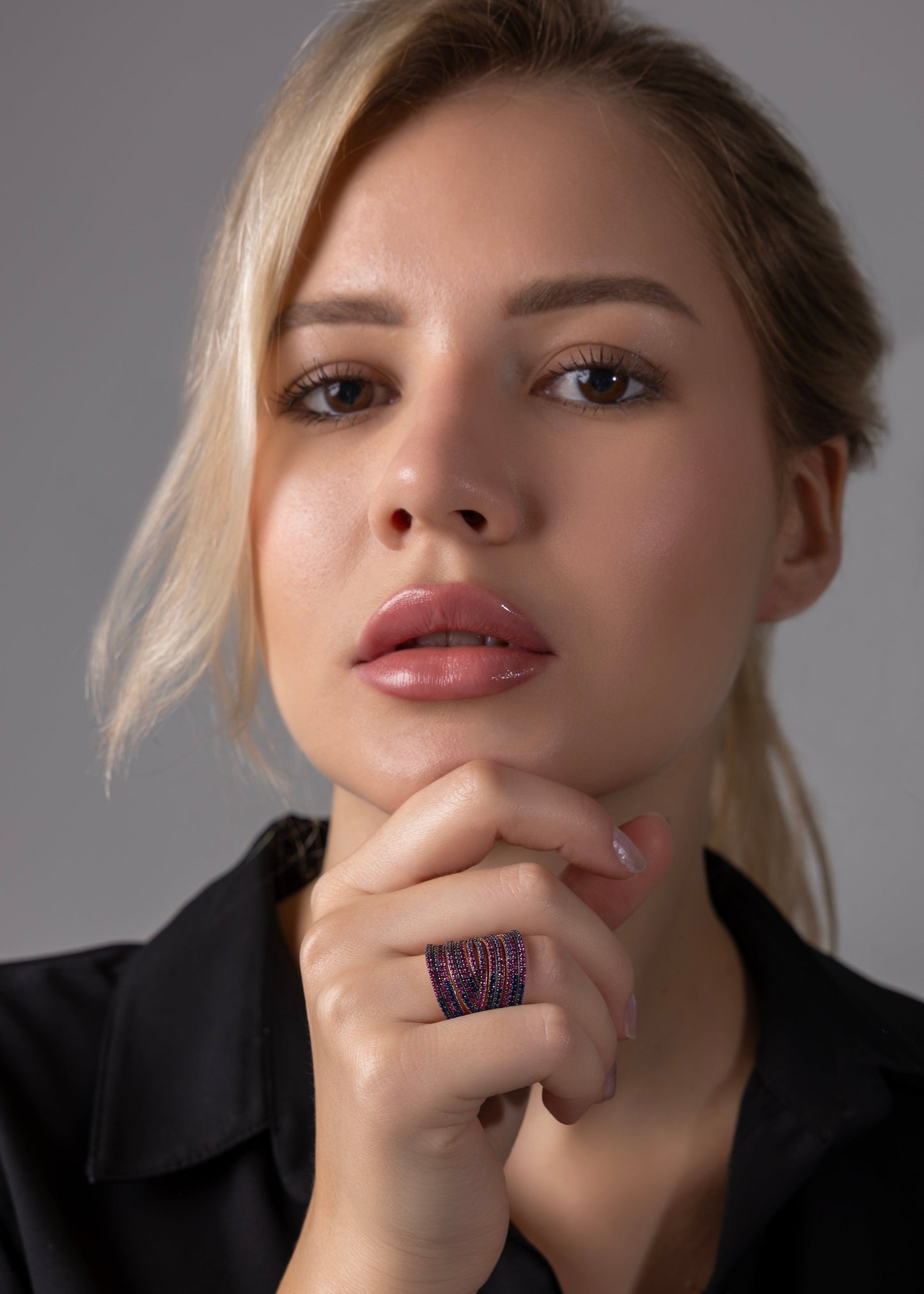 Woman with blonde hair and a black shirt against a gray background