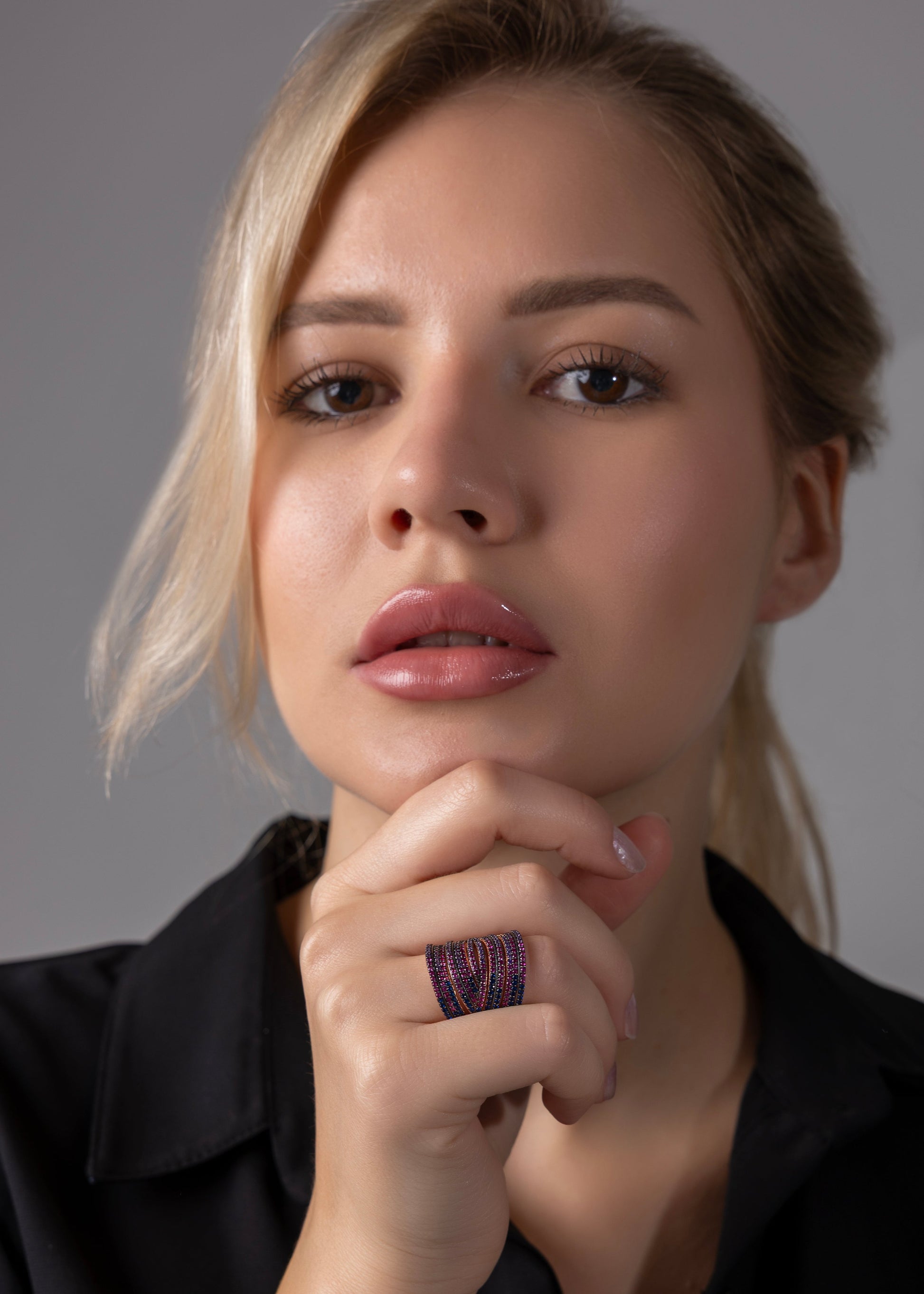 Woman with blonde hair and a black shirt against a gray background