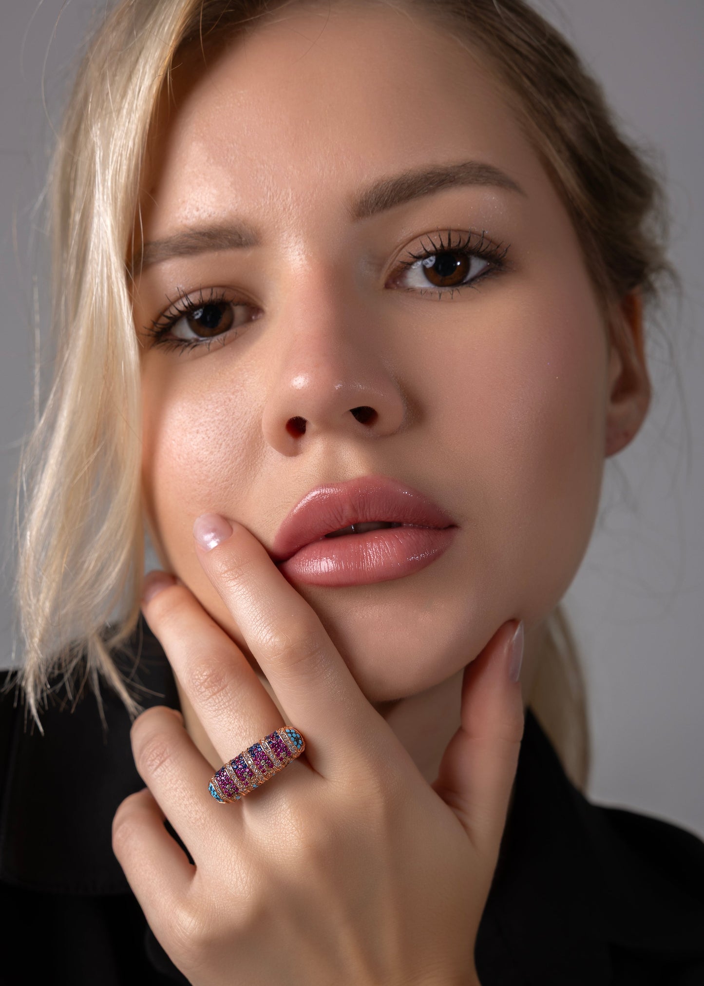 Woman wearing a ring with a visible gemstone against a neutral background