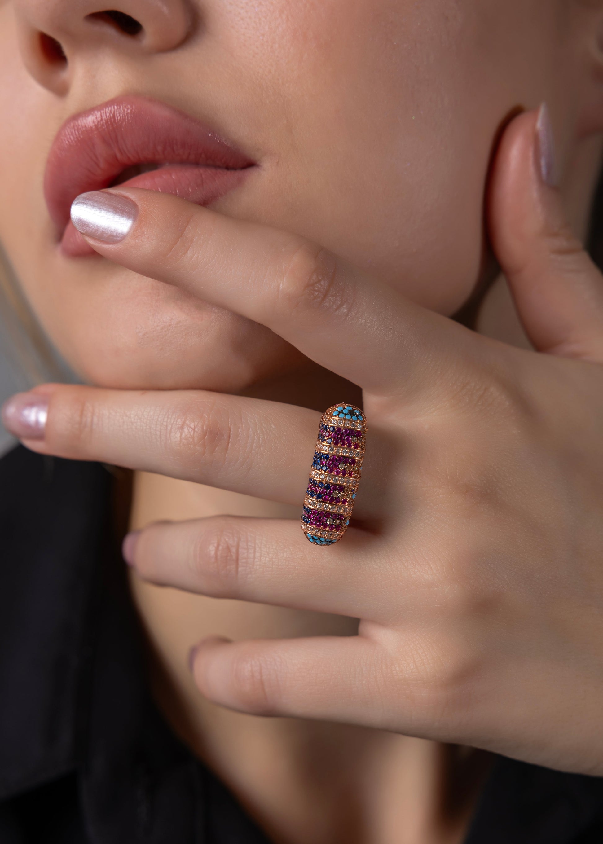 Close-up of a hand wearing a colorful ring with a blurred background