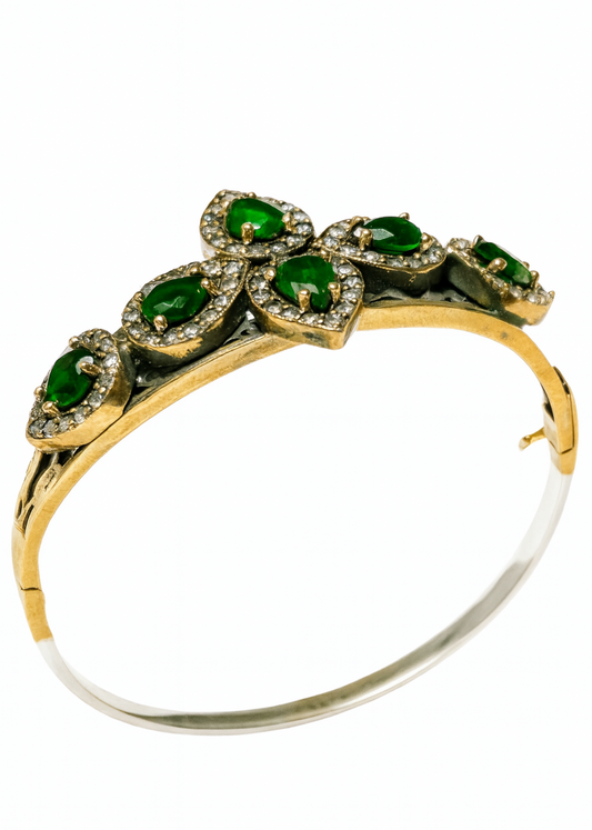 Gold and silver bracelet with green gemstones on a white background