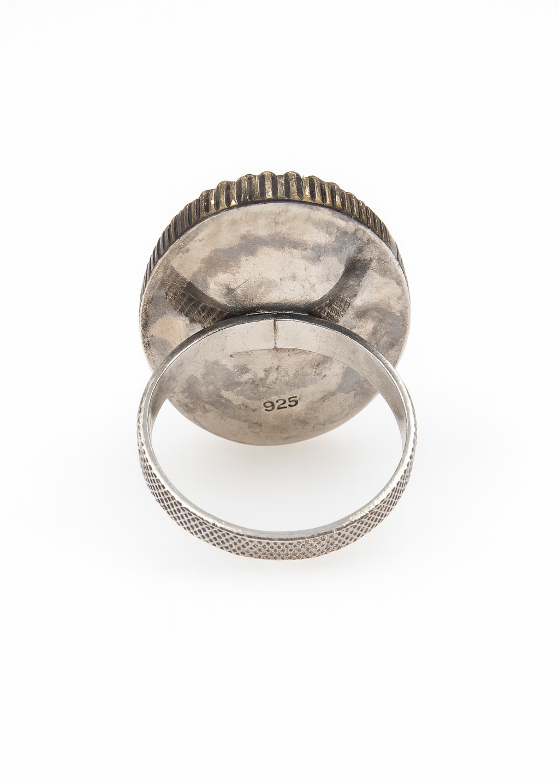 Silver ring with textured band and circular face on a white background