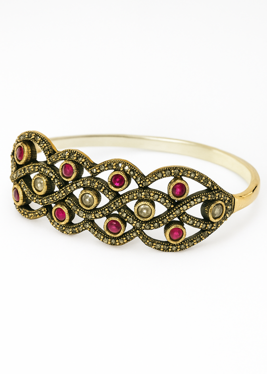 Gold bracelet with red gemstones on a white background
