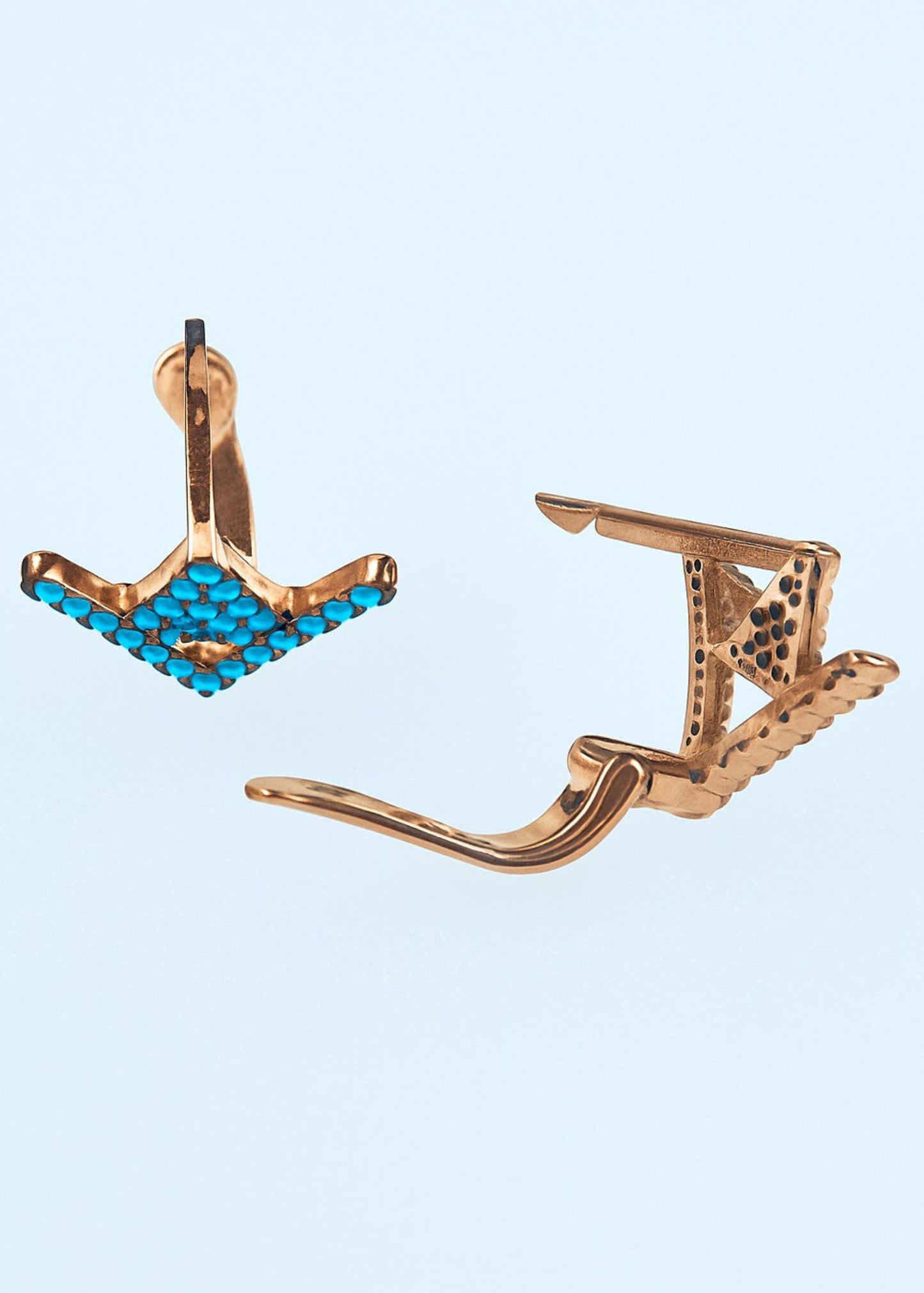 Pair of rose gold earrings with blue gemstones on a light blue background