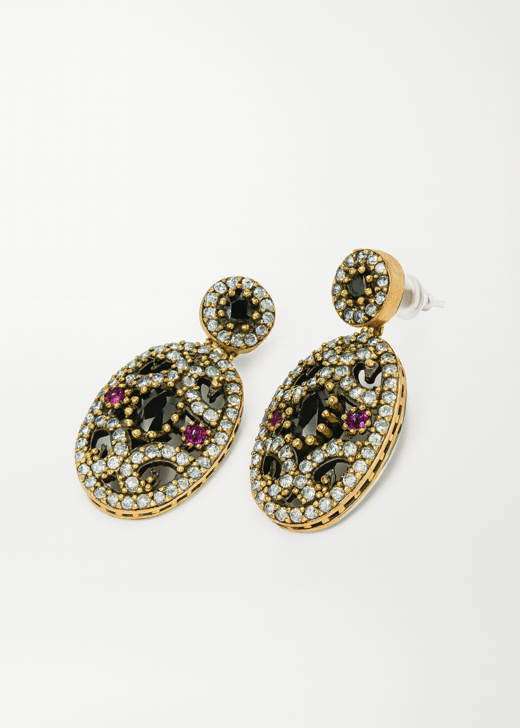 Pair of ornate earrings with gemstones on a white background
