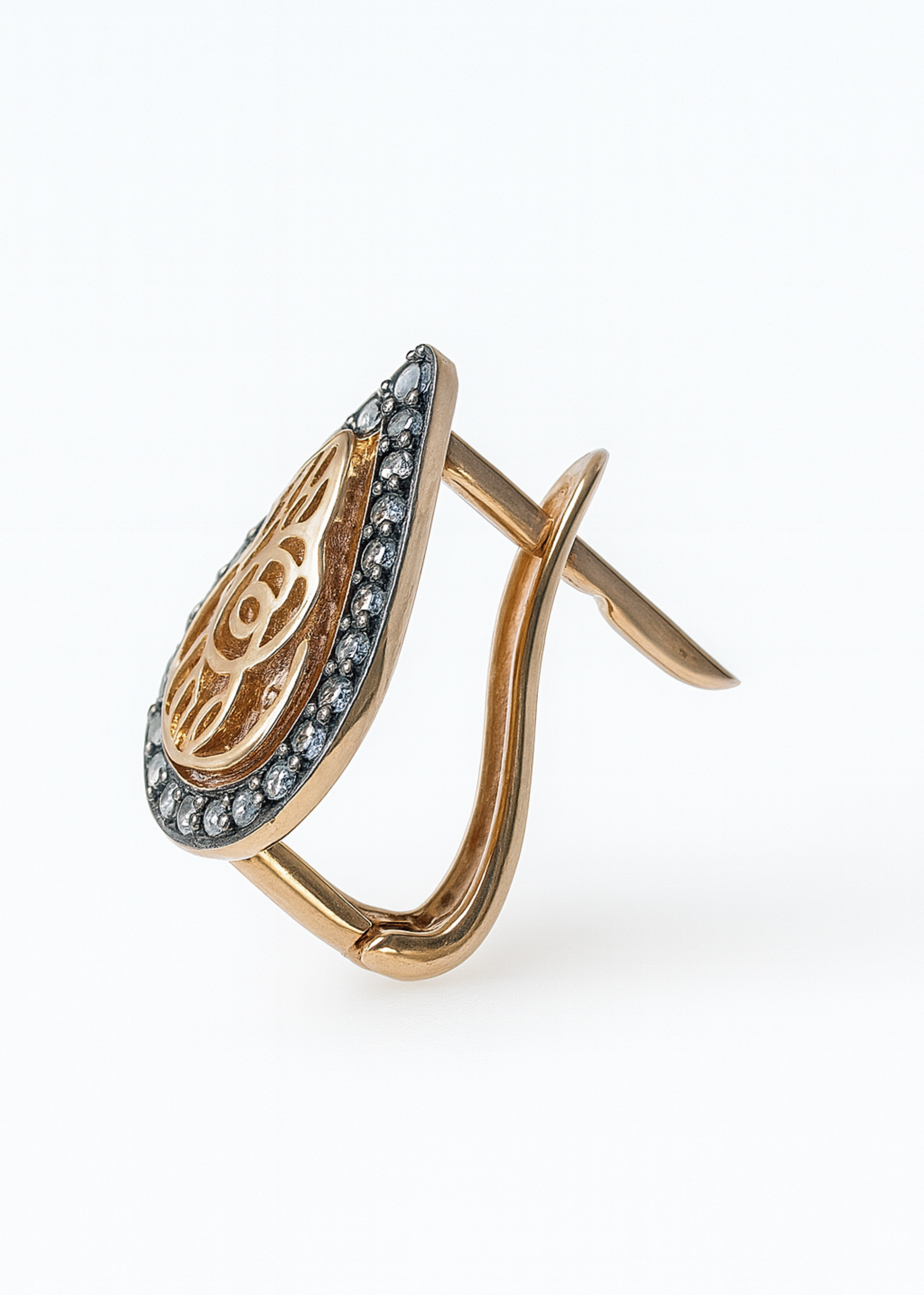 Gold earring with intricate design on a white background