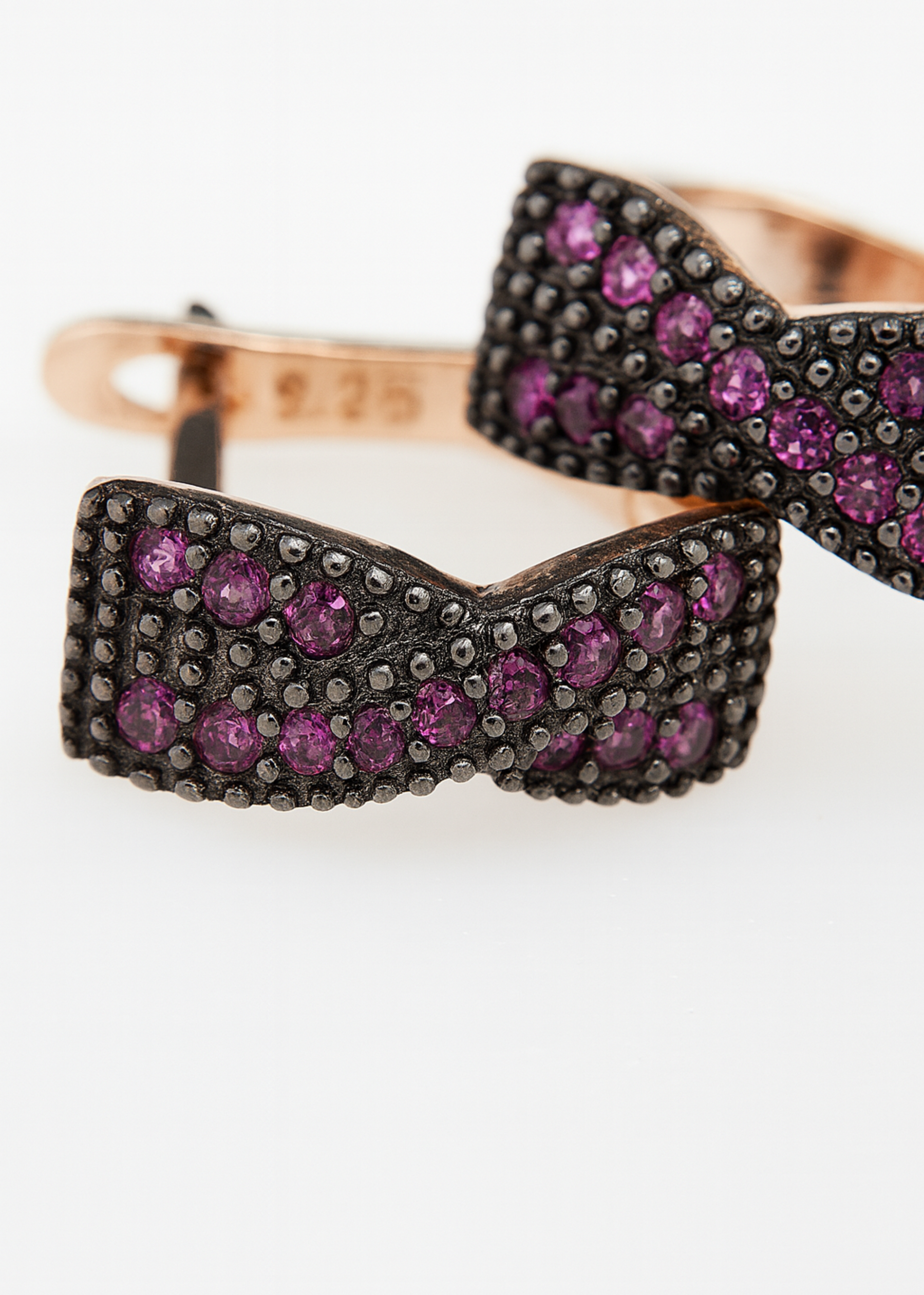 Bow-shaped jewelry piece with purple gemstones on a white background