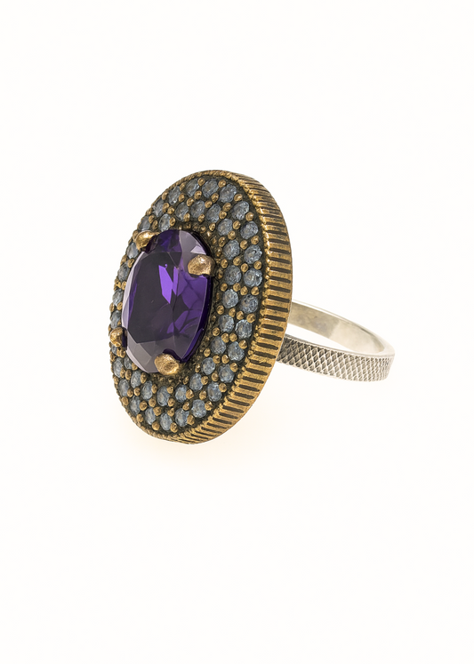 Elegant ring with purple gemstone and gold accents on a white background