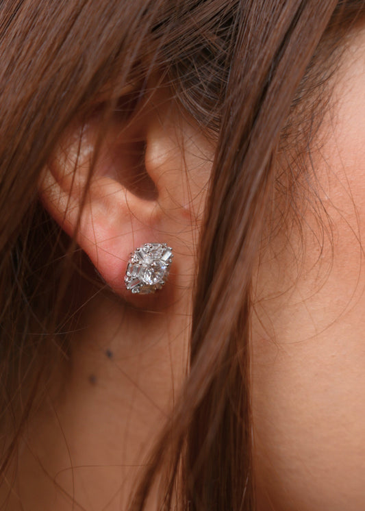 Close-up of an ear wearing a diamond stud earring with hair partially covering the frame.