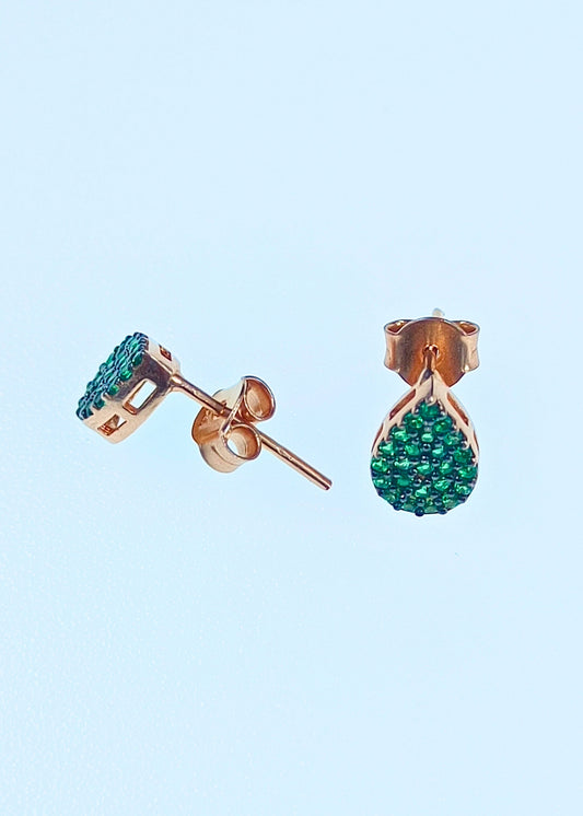 Rose gold earrings with green gemstones on a light blue background