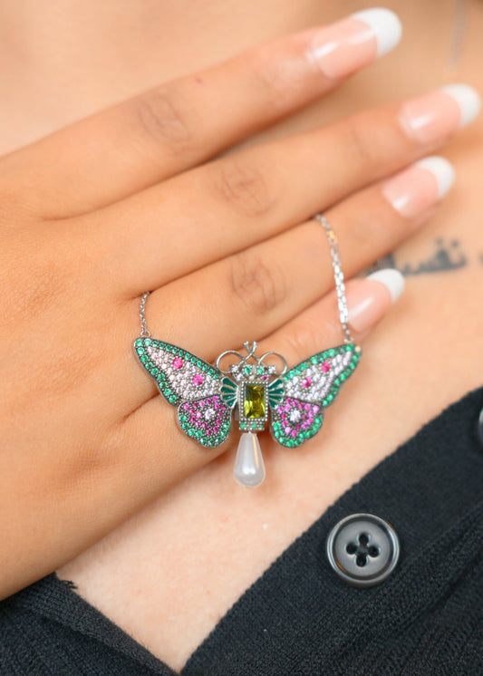 Butterfly-shaped pendant with gemstones held by a hand