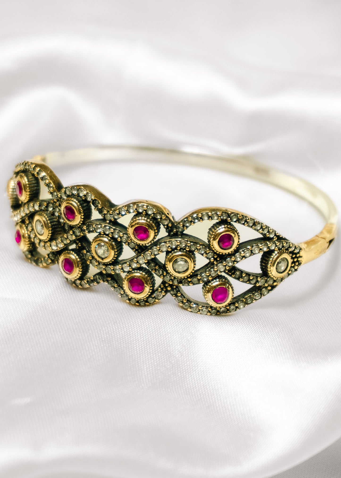 Gold bracelet with red gemstones on a white background