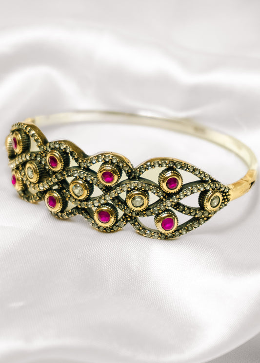 Gold bracelet with red gemstones on a white background