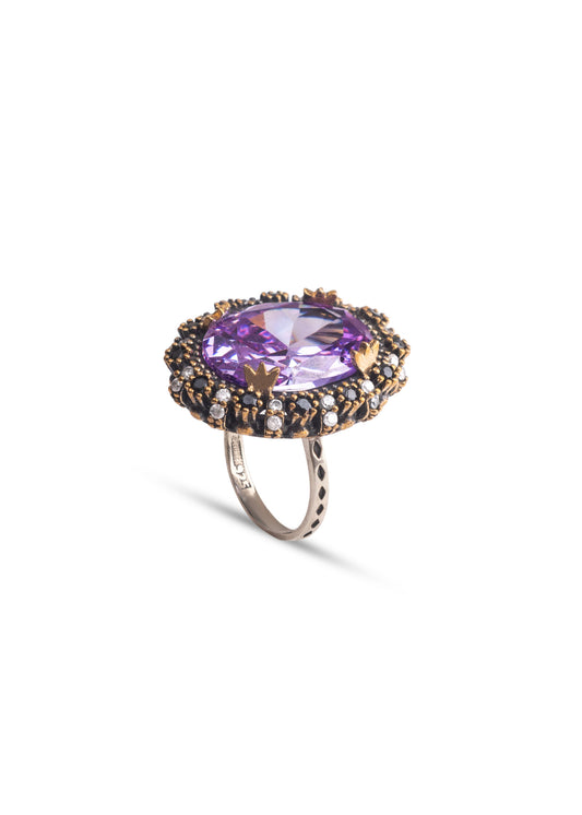 Ring with a purple gemstone and gold accents on a white background