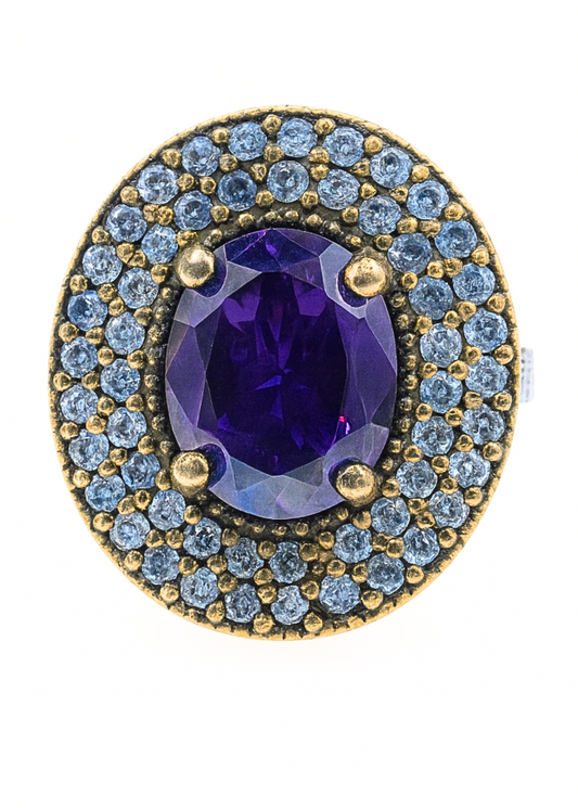 Jewelry ring with purple gemstone and blue gemstones on a white background