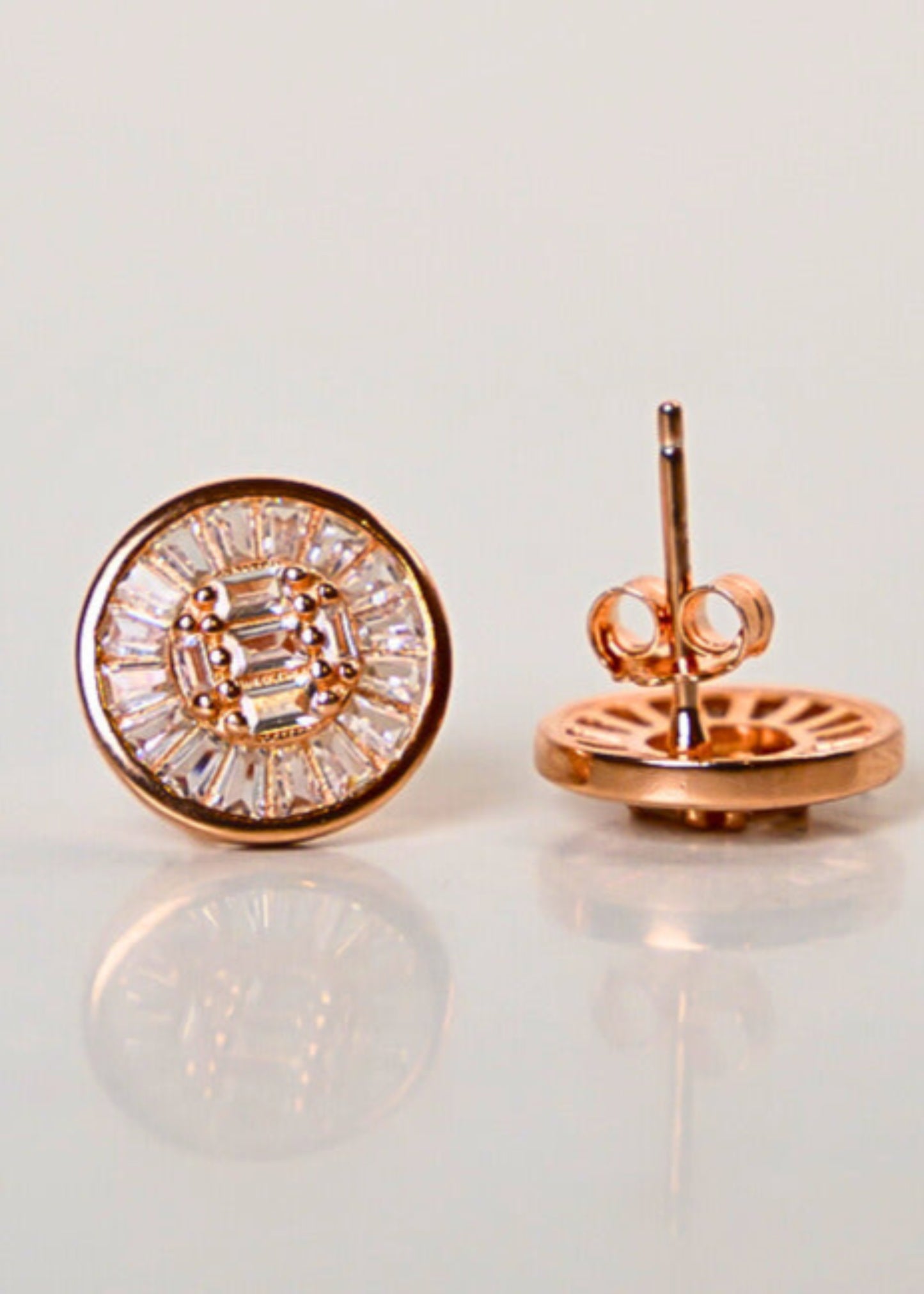 Rose gold emerald-cut diamond stud earrings on a light gray background