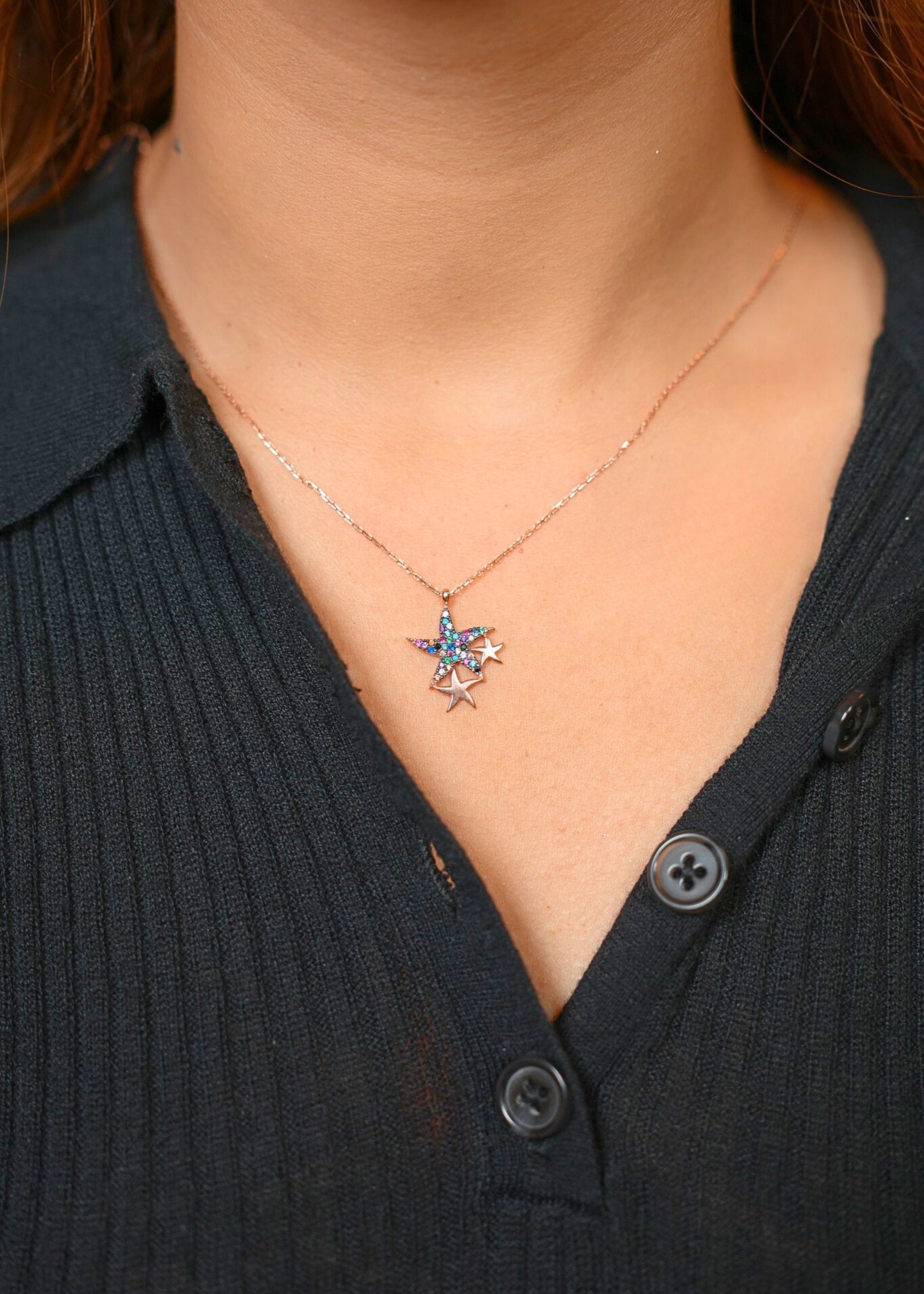Necklace with a star-shaped pendant worn by a person in a black shirt.
