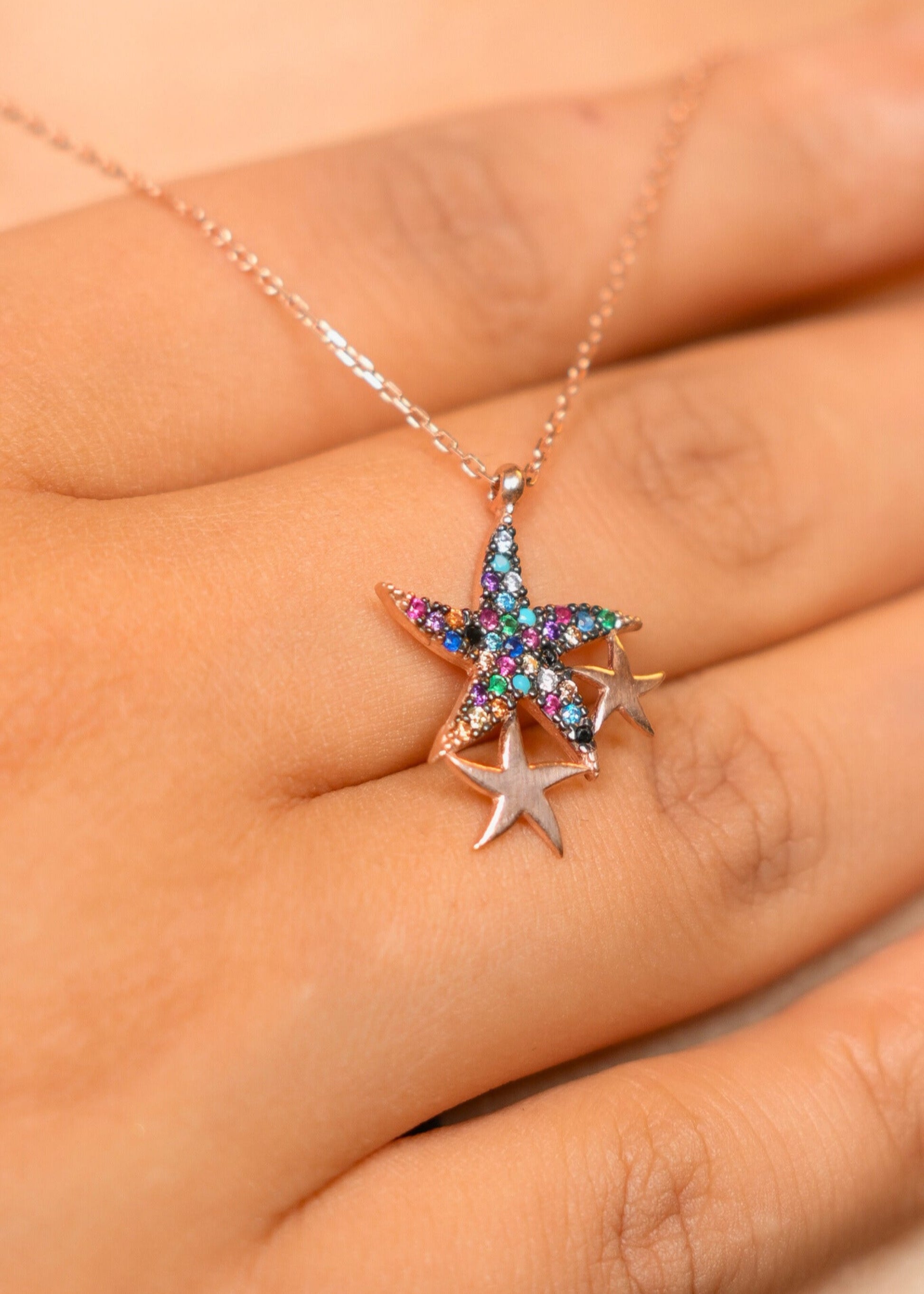Star-shaped necklace with colorful stones held in a hand