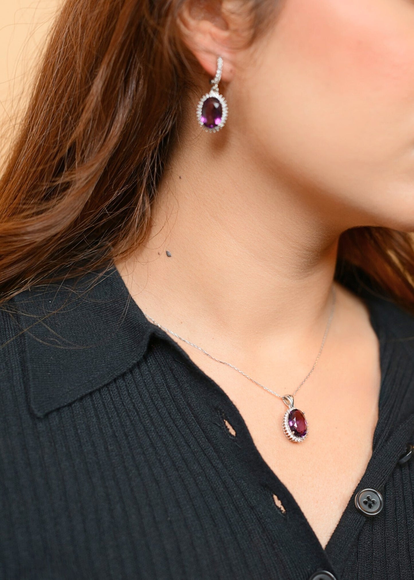 Close-up of a person wearing a necklace and earrings with gemstones.