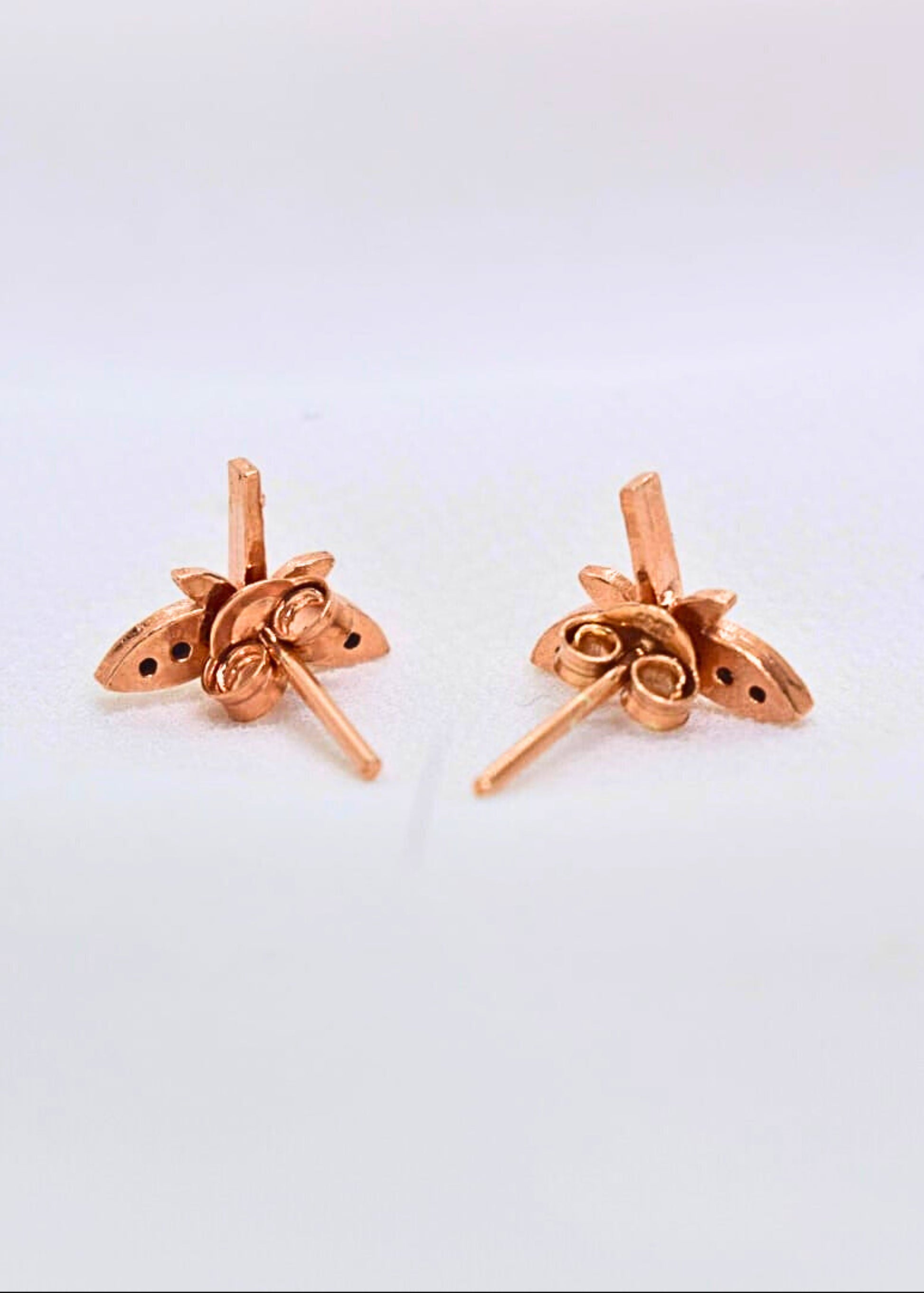 Pair of rose gold earrings on a light gray background