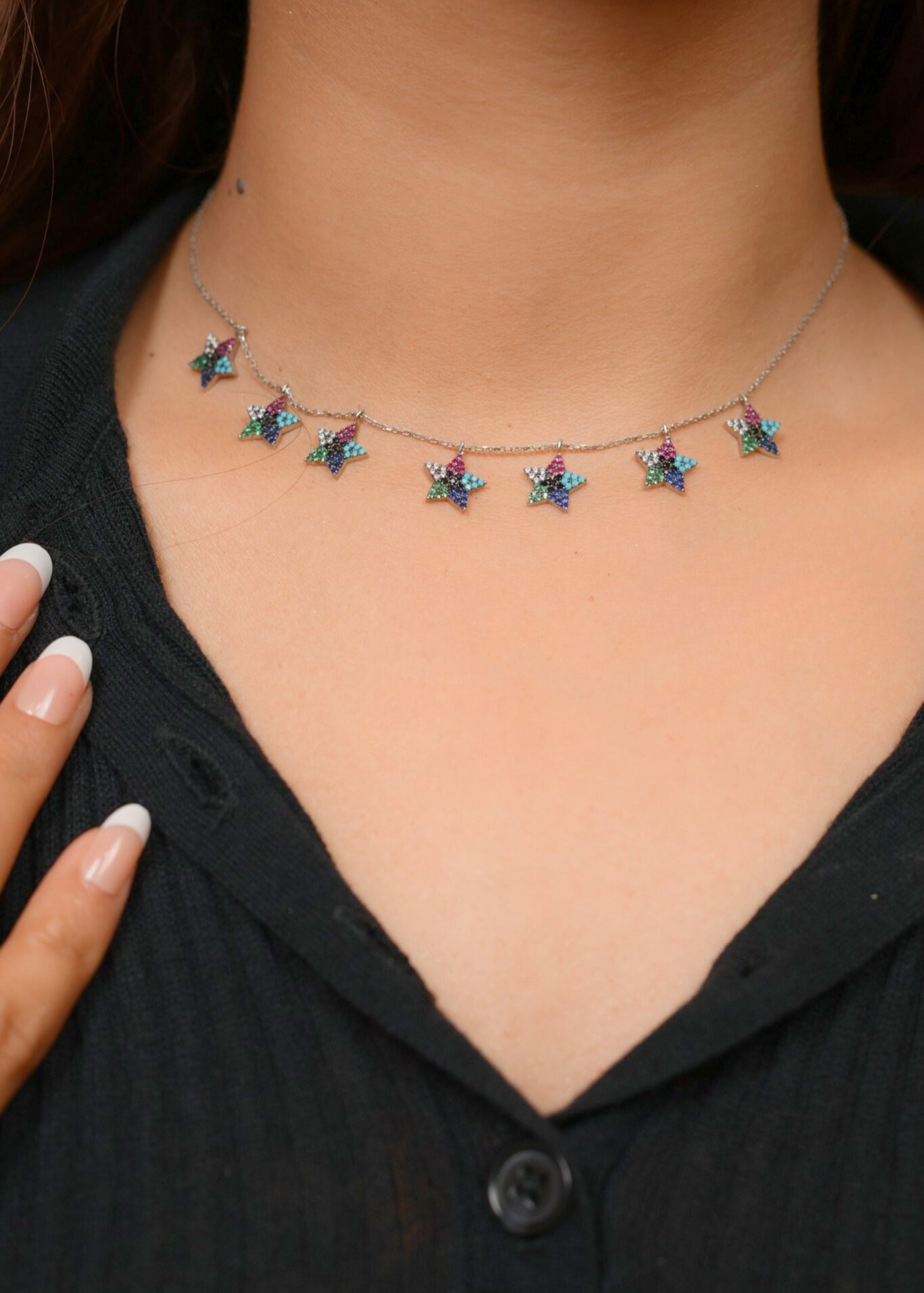 Necklace with colorful star-shaped pendants on a person wearing a black top.