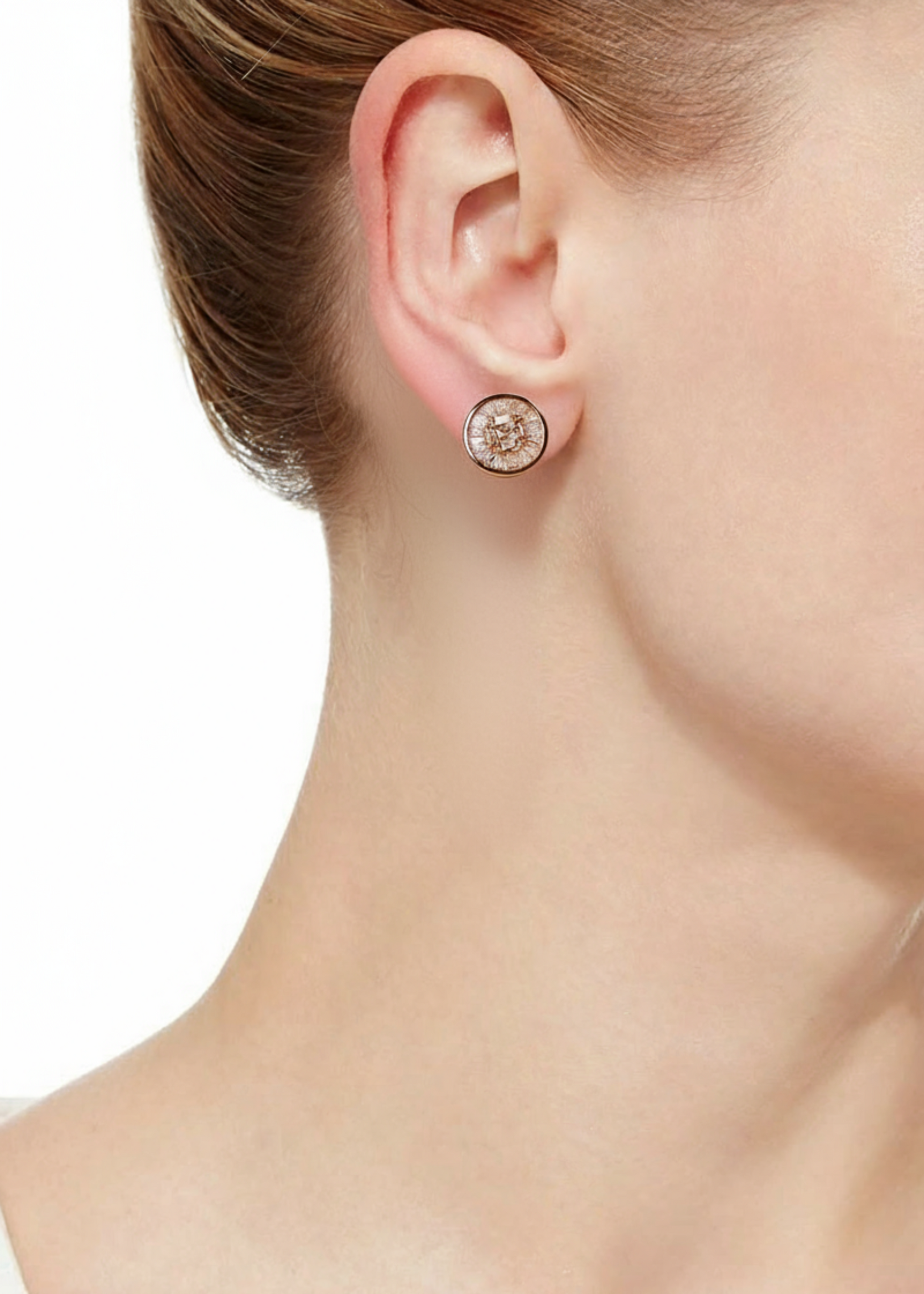 Close-up of a diamond earring on an ear with a neutral background